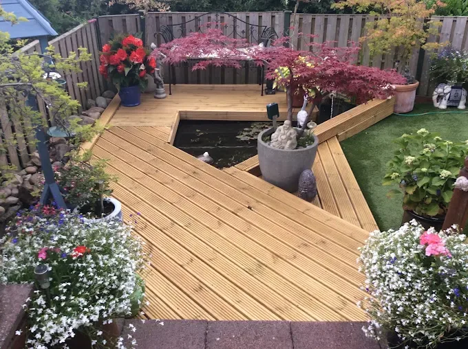 Timber decking around a garden pond with mature planting