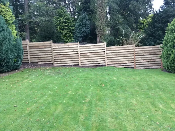 Modern horizontal slatted timber fence in a landscaped garden